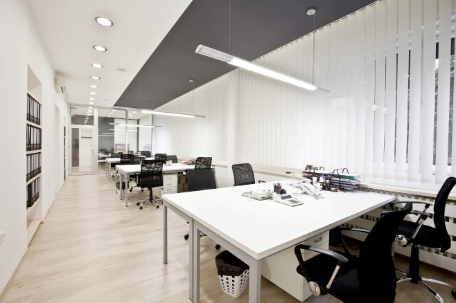 Professional office space with rows of white desks and black chairs